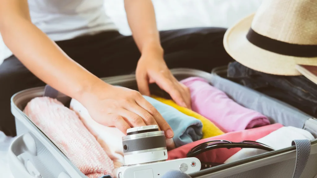 スーツケースに旅行用の荷物を入れる人